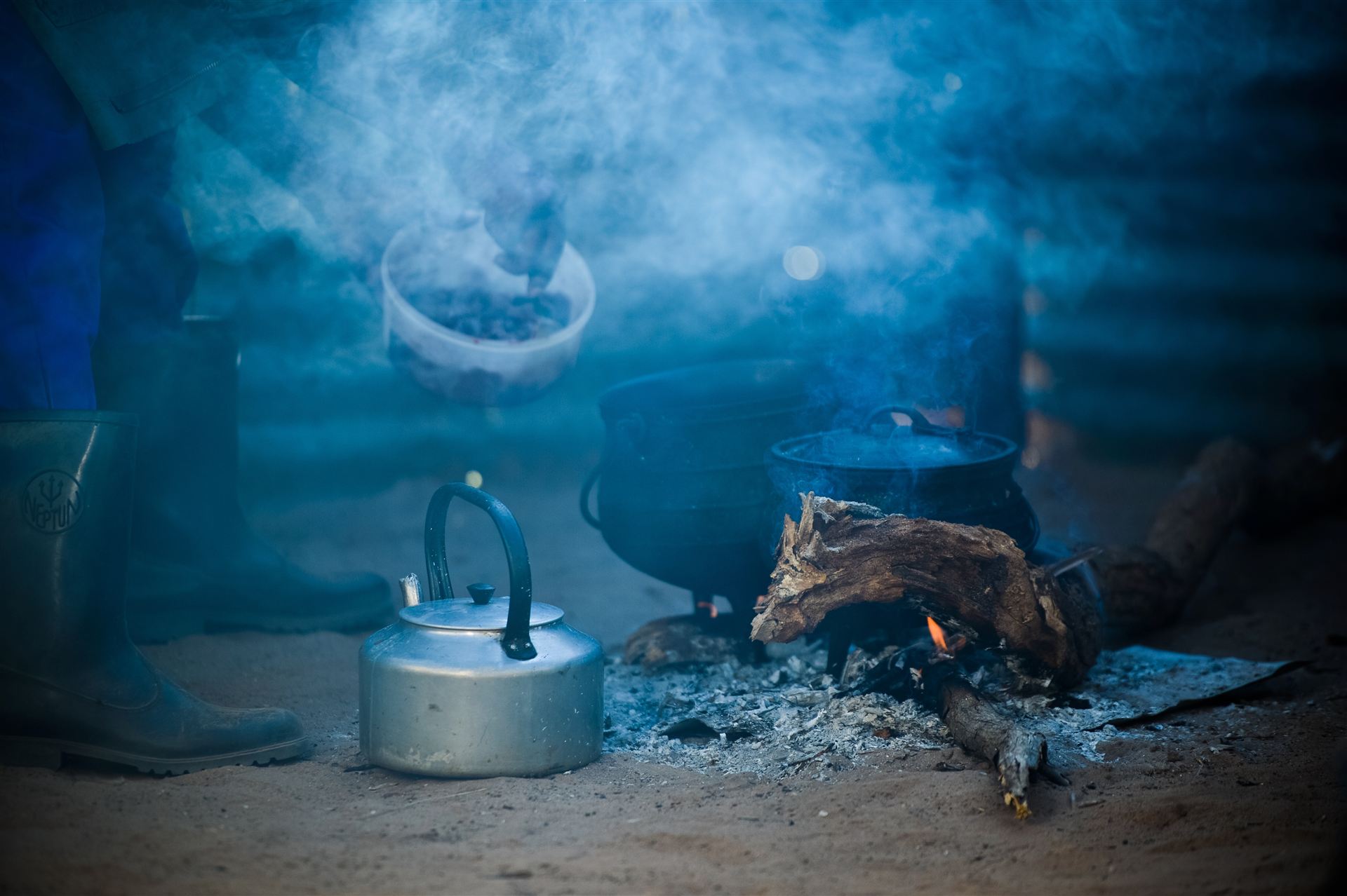 Kettle and three-legged pots over a smoky fire